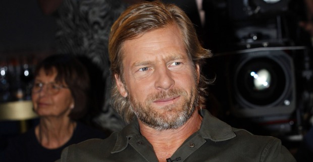 Schauspieler Henning Baum mit einem schwarzen Hemd und leicht gegolten blonden Haaren. Er trägt einen Dreitagebart.