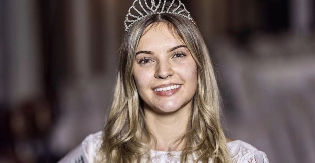 Eine ungeschminkte Frau mit Krone auf dem Kopf und blonden langen Haaren.