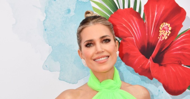 Sylvie Meis im grünen Kleid vor einer roten Blüte im Hintergrund