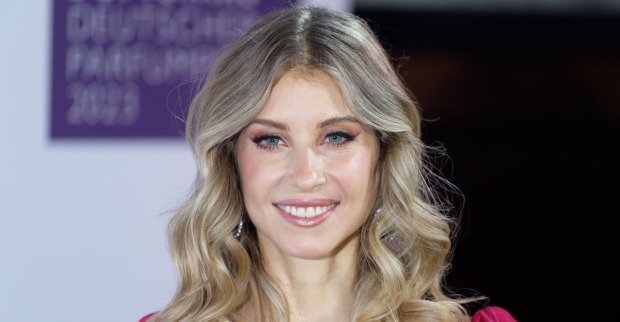Cathy Hummels trägt offene, blond gewellte Haare und ein starkes Augen Make-Up.