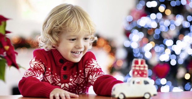 Kind freut sich über Spielauto zu Weihnachten.