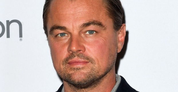 Leonardo DiCaprio steht vor einer weißen Fotoleinwand.