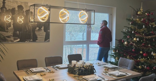 Karl Nehammer vor einem festlich gedeckte Tisch und dem Weihnachtsbaum. Er schaut aus dem Fenster.