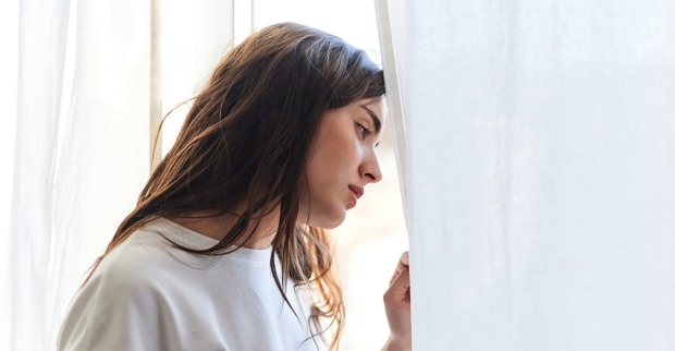 Frau steht am Fenster und grübelt | Credit: iStock.com/Javi Sanz