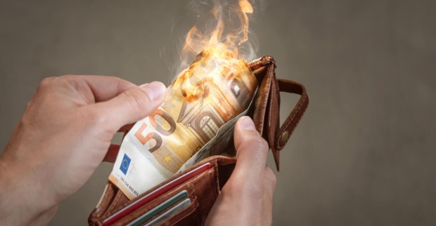 Eine Mann öffnet eine Geldtasche. Der 50-Euro-Schein darin brennt