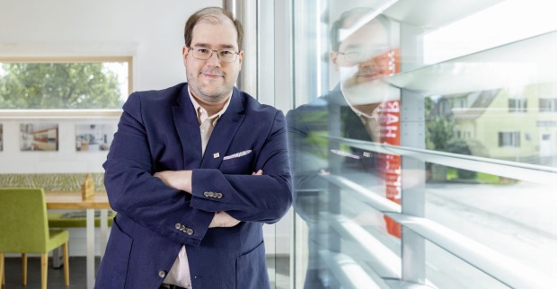 Yves Suter, GF Hartl Haus, lehnt sich an eine Glaswand | Credit: Julia Dejmek