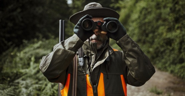 Ein Jäger mit Fernglas-Gucker unterwegs im Wald.