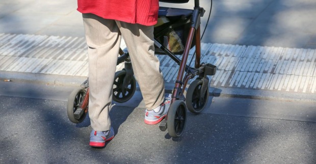 Eine Frau ist mit einem Rollator unterwegs.