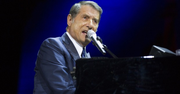 Udo Jürgens singt auf einer Bühne und spielt dabei auf einem Klavier.