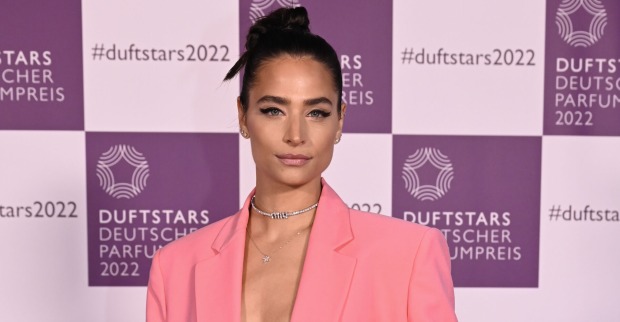 Amira Pocher mit geschlossenen schwarzen Haaren und einem rosa Outfit.