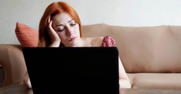Frustrierte Frau vor ihrem aufgeklappten Laptop