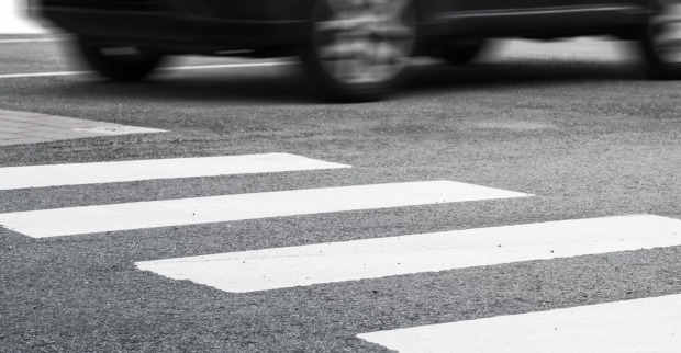 Eine Auto braust auf einem Zebrastreifen davon.