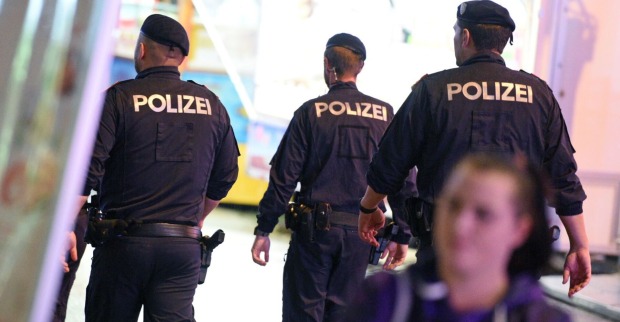 Drei Polizisten von hinten bei einem Einsatz.