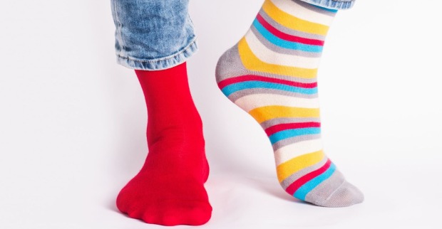 Jemand, der einen roten und einen bunt gestreiften Socken trägt.