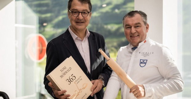 Mann mit Kochbuch und Koch mit Nudelholz