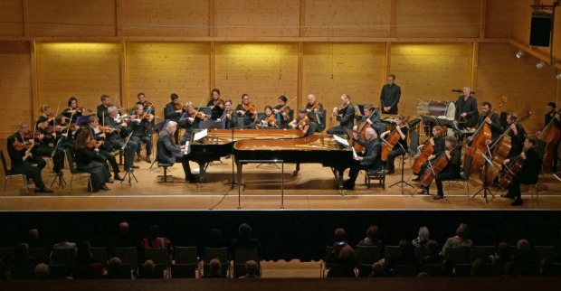 Orchester mit Pianisten, Chello- und Geigenspieler vor einem Publikum