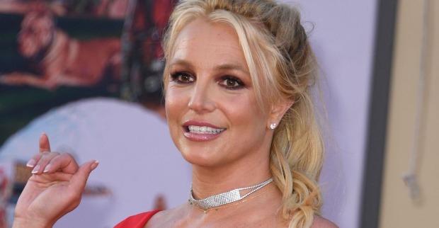 Britney Spears mit geschlossenen blonden Haaren und einer glitzer Kette.