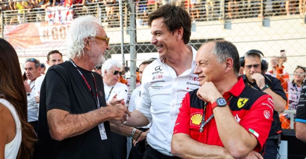 Flavio Briatore, Toto Wolff und Frédéric Vasseur stehen lachend zusammen.