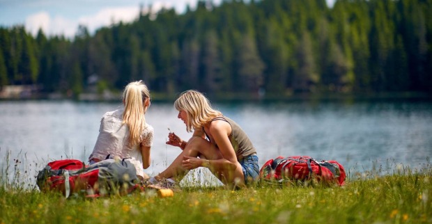 2 junge Frauen, die beim Ufer eines Sees sitzen