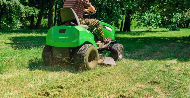Ein Mann sitzt auf einem Rasenmäher-Traktor