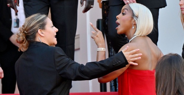 Kelly Rowland auf dem roten Teppich. Sie trägt blonde Haare und ein rotes Kleid und streitet mit dem sicherheitspersonal.