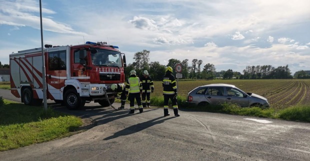 Ein Feuerwehrauto, Einsatzkräfte und ein Pkw im Straßengraben