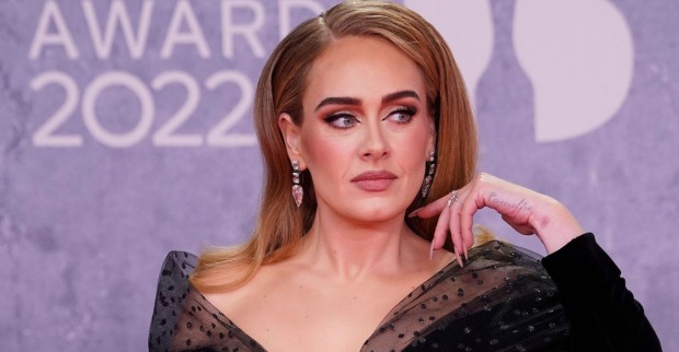 Adele mit starken Make Up und offenen Haaren bei einem Event. Sie schwingt mit ihrer Hand ihre Haare zurück.