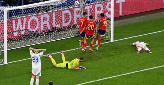 Vor dem Tor eines Fußballfeldes liegen zwei Männer, drei jubeln daneben