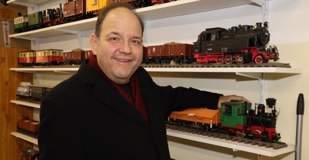 Gerald Pichowetz mit einem schwarzen Mantel und Modellbahnen.