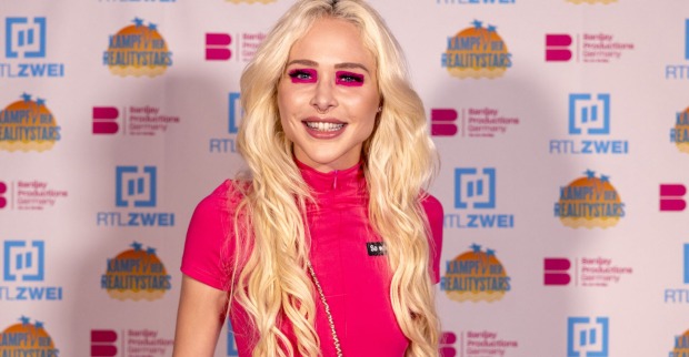 Theresia Fischer mit offenen blonden gewellten Haaren und einem pinken Outfit.