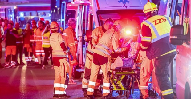 Blaulicht und Einsatzfahrzeuge bei Nacht, Rettungskräfte kümmern sich um Verletzte.