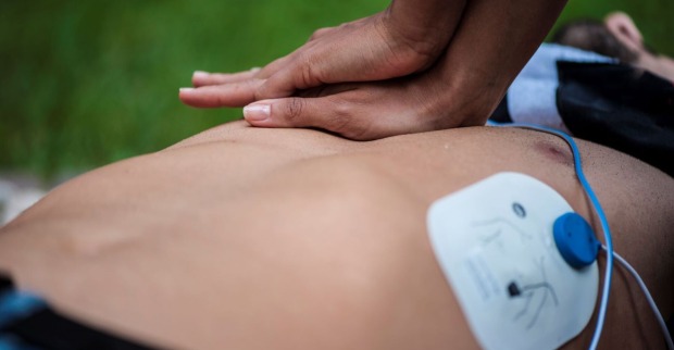 Rettungskraft führt Herzdruckmassage durch. Ein Defibrillator ist im Einsatz.