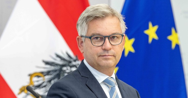 Magnus Brunner, EU-Kommissar in spe, vor der österreichischen und der EU-Flagge im Porträt