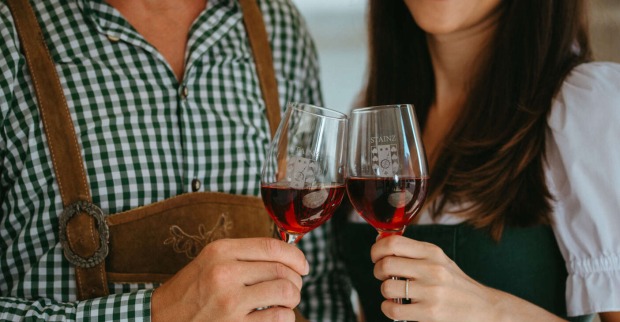 Mann und Frau in Tracht stoßen mit einem Wein an