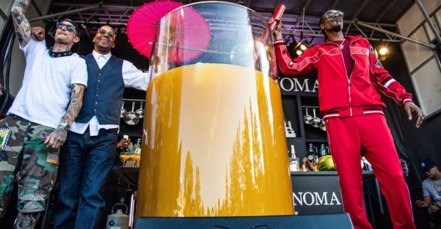 Der Rapper Snoop Dogg auf einer Bühne neben einem 500 Liter-Cocktail in einem überdimensional großen Glas samt Strohhalm