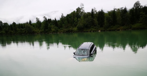 Kraftfahrzeug im Fluss Drau umgeben von Baumlandschaft