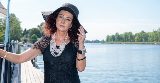 Eine Frau in schwarzem Outfit steht neben einem Fluss