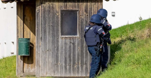 Zwei Polizeibeamten hinter einem Holzhäuschen.