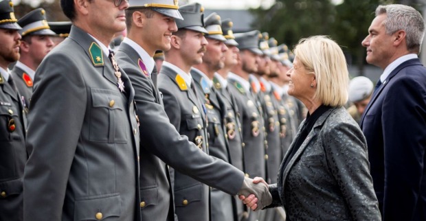Ein Soldat reicht Verteidigungsministerin Klaudia Tanner (ÖVP) bei der Ausmusterung an der Theresianischen Militärakademie die Hand, im Hintergrund Bundeskanzler Karl Nehammer (ÖVP)