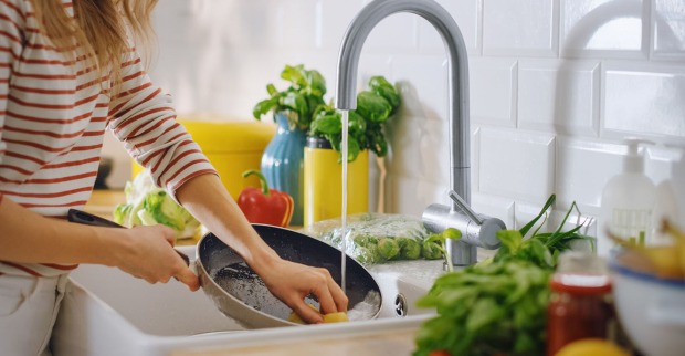 Frau reinigt Pfanne | Credit: iStock.com/gorodenkoff