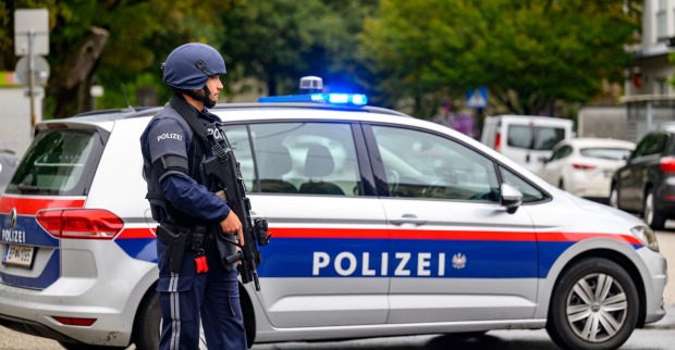 Ein bewaffneter Polizist steht vor einem Polizeiauto.