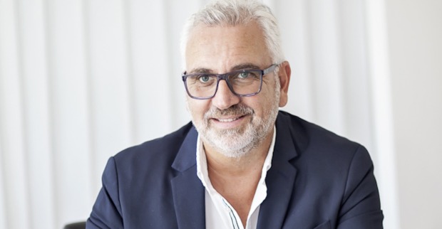 Mann mit weißem Haar und dunkelblauen Sakko