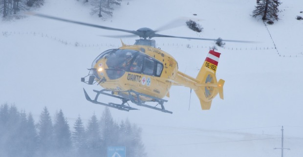 Gelber ÖAMTC-Rettungshubschrauber in einem Skigebiet.