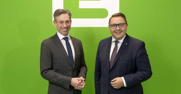 Zwei Männer in Anzügen stehen vor einer grünen Wand