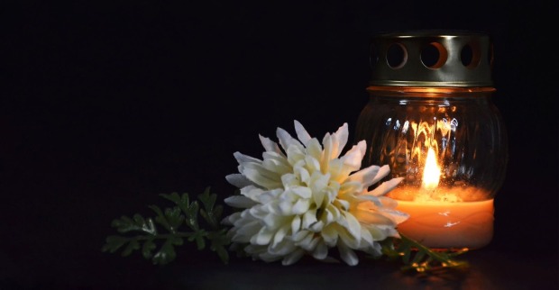 Leuchtende Trauerkerze und weiße Chrysantheme auf dunklem Hintergrund