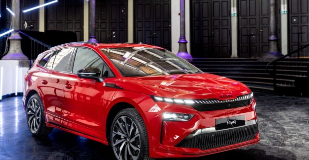 Ein roter Skoda Enyaq steht in einer Halle mit vielen Säulen. Das Auto leuchtet im Licht der Lampen. Die Scheinwerfer des Autos sind eingeschaltet.