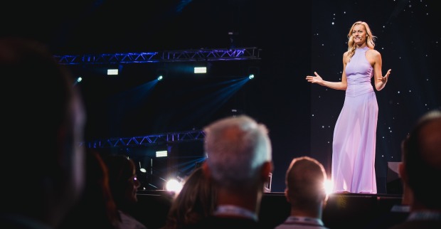 Miriam Höller steht in einem lila Kleid auf der Bühne.