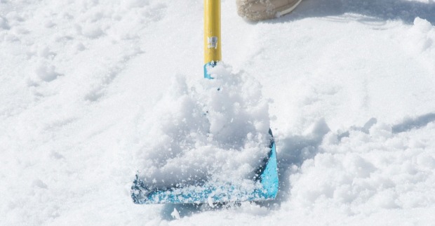 Person schaufelt Schnee mit Schneeschaufel