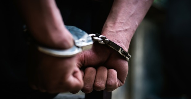 Mann trägt Handschellen hinterm Rücken