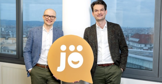 jö-Gescheftsführer Nikolai Scheurecker und Johannes Greller halten das jö-Logo: eine beigefarbene Sprechblase mit weißer, fetter Schrift "jö" innen